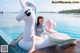 A woman sitting on an inflatable unicorn float in a pool.