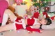 A woman in a santa outfit laying on the floor next to a Christmas tree.