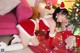 A woman in a santa outfit is posing in front of a Christmas tree.
