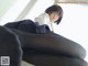 A woman in a white shirt and black pantyhose sitting on a couch.