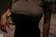 A woman in a gray shirt is holding a white purse.