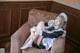 A woman in a maid outfit sitting on a couch.