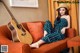 A woman sitting on a couch with a guitar.